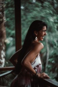 Image of Ana Montano near a fence with a blurry background of trees. 