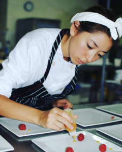Image of Chef Justine adding details to a plate of food. 