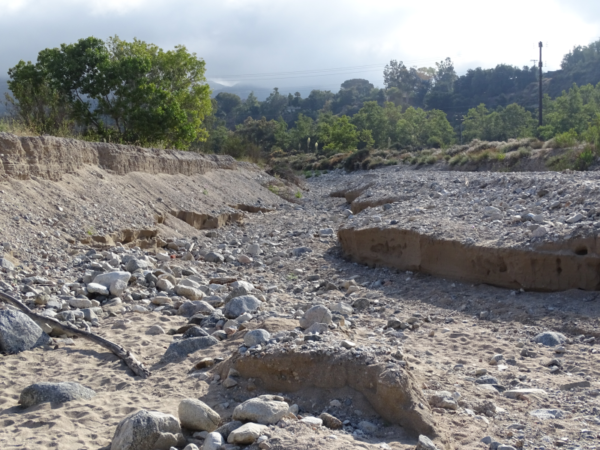 The dry streambed shows erosion caused by strong flow in the winter months.