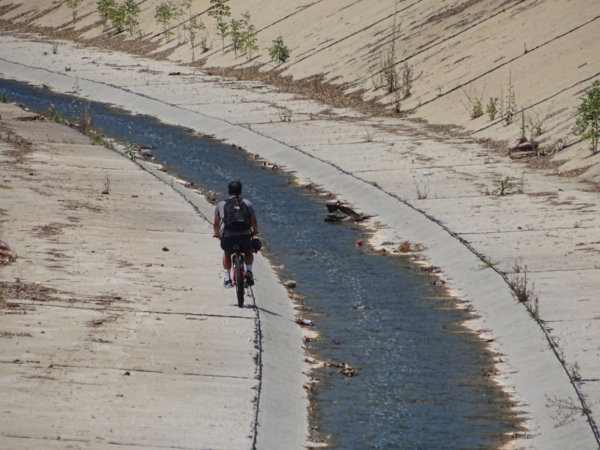 A man on a bicycle riding in the channel.