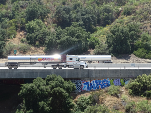 A truck crossing on a freeway crossing a bridge. Graffiti is visible on the bridge.
