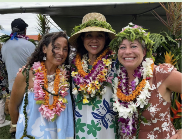 Three teachers with garlands of flowers around their neck- lei- and dressed in tropical  dresses and leaf crowns around their head 