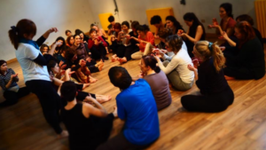 An image of many people sitting around in a circle at a workshop.