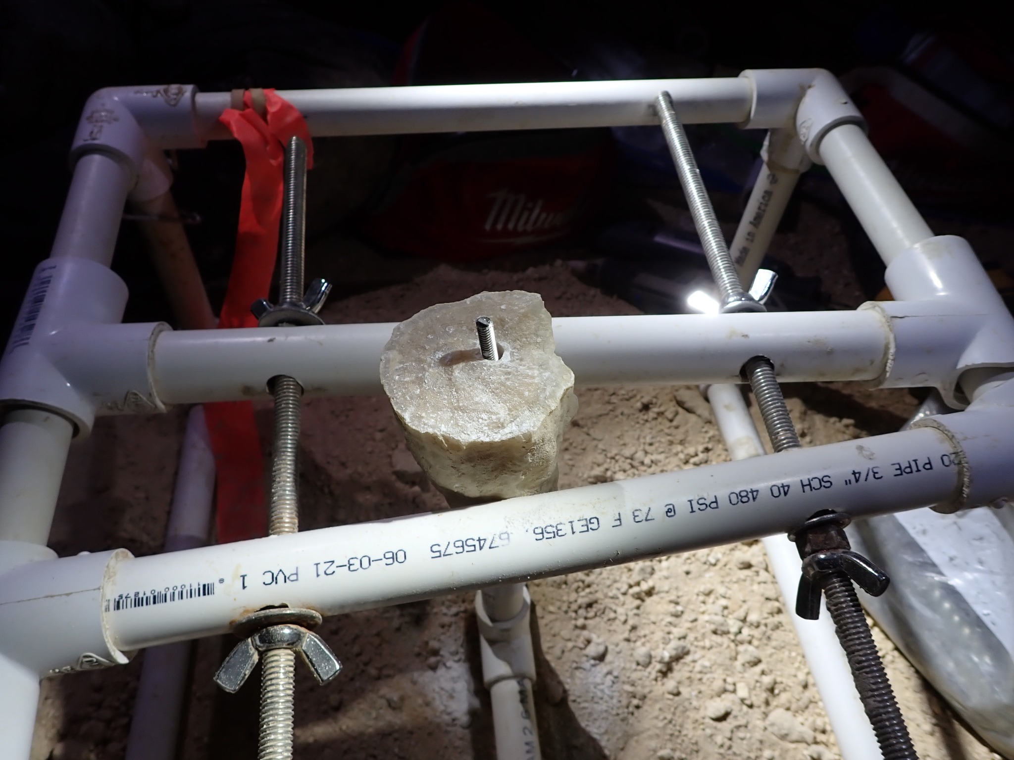 a broken speleothem is hold using a PVC-frame tool called Speleoclamp